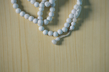 Prayer beads white for Ramadan, isolated on a wood background