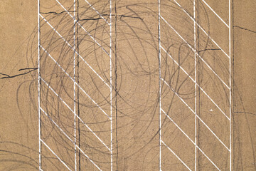 A top down, aerial view directly above an empty parking lot with drift tire marks on a sunny day....