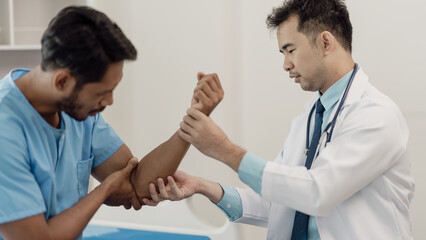 Physical therapist doing physical therapy on male patient with muscle injury in arm, healthy...