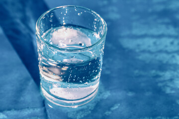 A glass of drinking water on blue background. Splashing water from glass