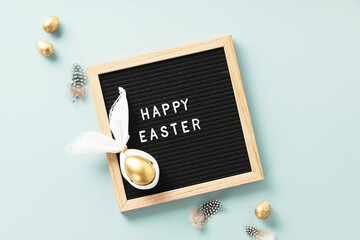letter board, egg in easter bunny napkin, golden eggs, feathers and spring flowers