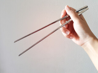 Woman hand holding silver chopsticks isolated on white background.