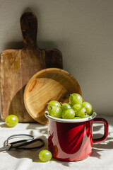 Gooseberries in a red enamel mug in sunlight