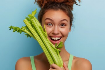 Naklejka premium Happy beautiful woman holding celery stalk on blue background