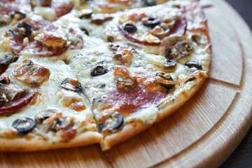 Closeup sliced pepperoni and mushroom pizza on wood