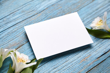 A blank landscape-oriented card on a rustic blue wooden table, elegantly framed by white...