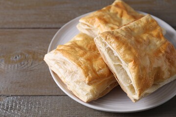 Delicious fresh puff pastries on wooden table, closeup. Space for text