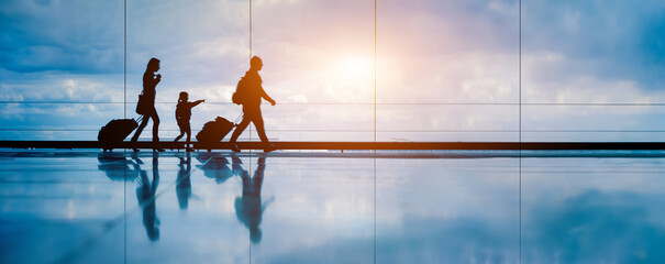 Family at airport travelling with young child walking to departure gate. Family vacation and holidays concept with silhouette of parents and kid. Travel lifestyle banner or background for air travel. - obrazy, fototapety, plakaty