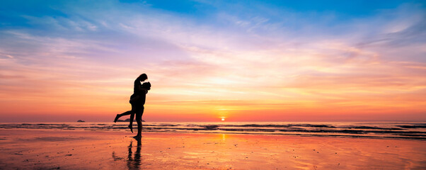 Silhouette of romantic couple kissing at sunset on a serene beach, enjoying a dreamy vacation in...
