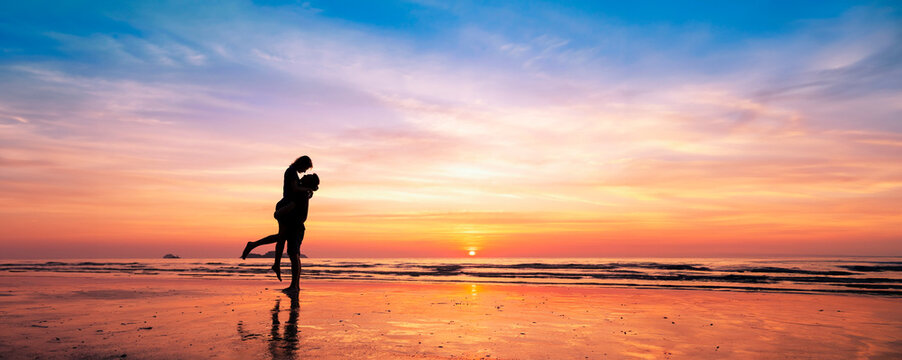 Silhouette of romantic couple kissing at sunset on a serene beach, enjoying a dreamy vacation in warm tropical holiday destination. Love, romance, honeymoon, Valentine's day.