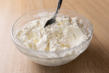 Sour cream is added to sour milk cheese and mixed.