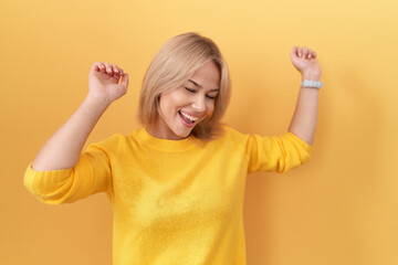 Young caucasian woman wearing yellow sweater dancing happy and cheerful, smiling moving casual and confident listening to music