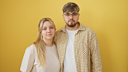 A young man and woman stand close together, expressing unity against a vibrant yellow background.