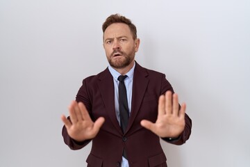 Middle age business man with beard wearing suit and tie moving away hands palms showing refusal and denial with afraid and disgusting expression. stop and forbidden.