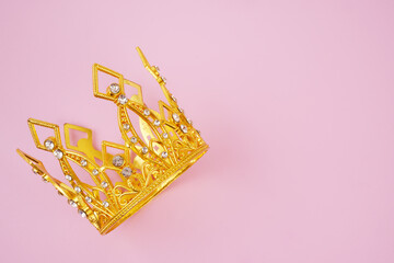 Gold princess crown on pink background, copy space for text.