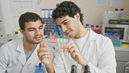 Two men scientists examining test tubes together in a laboratory setting
