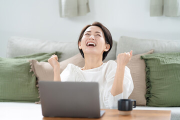 パソコンを見てガッツポーズする女性