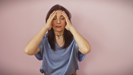 Hispanic mature woman in distress with a headache isolated over a pink background, appearing...