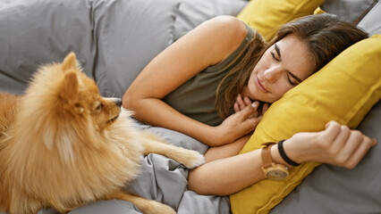 Exhausted but beautiful young hispanic woman sleeping comfortably with her cuddly dog in the cozy...