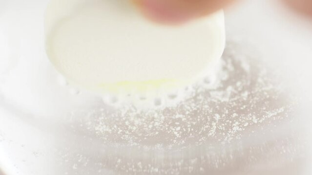 Round tablet of soluble aspirin bubbling in glass of water, macro shot. Effervescent tablet vitamin C in glass, close up. Sport medication, healthy lifestyle. Fizzing bubbles in water