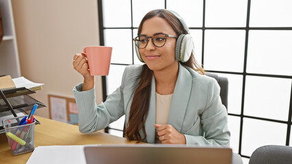 Impressive young hispanic female boss dominates the business world, multitasking with laptop,...