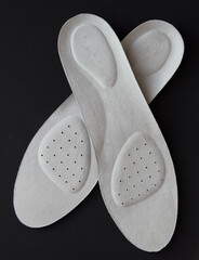 Leather orthopedic insoles on black background. Foot care products.