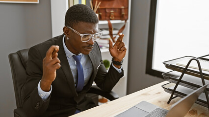 African american businessman crossing fingers for good luck in a modern office