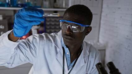 African man in lab coat and safety goggles conducting research in a science laboratory