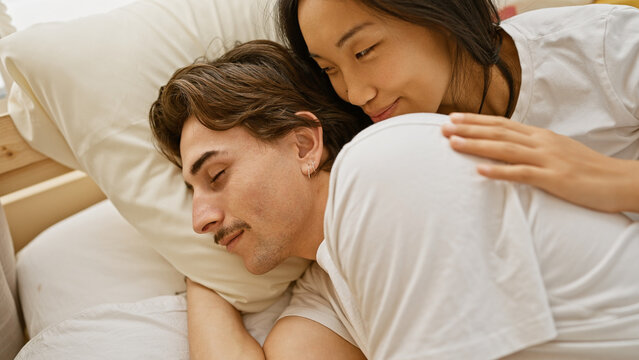 A loving interracial couple cuddling in a cozy bedroom setting, portraying warmth and affection. - Powered by Adobe