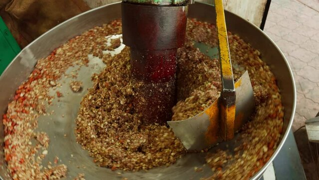 Worker using machinery to crush organic seeds for to extract oil in the mill