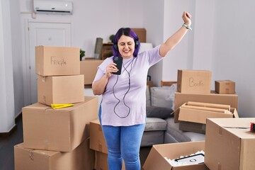 Young beautiful plus size woman listening to music dancing at new home