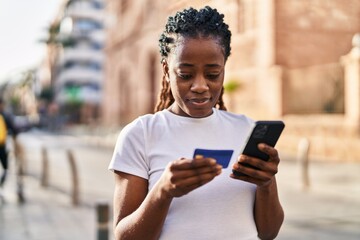 Fototapeta na wymiar African american woman using smartphone and credit card at street