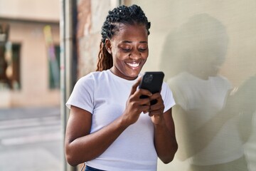 Fototapeta na wymiar African american woman smiling confident using smartphone at street