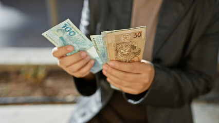 Young woman holding brazilian reais on a city street, conveying a sense of finance, travel, and...
