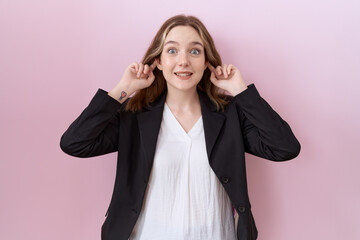 Young caucasian business woman wearing black jacket smiling pulling ears with fingers, funny...