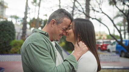 Fototapeta premium A loving couple embraces on a city street, their affectionate moment captured against an urban outdoor backdrop.