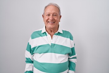 Senior man with grey hair standing over white background with a happy and cool smile on face. lucky...