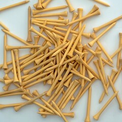 A pile of natural wood colour 70mm bamboo golf tees lying on a white surface