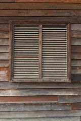 Fototapeta na wymiar Closed wooden shutters on the window of an old brown shabby house
