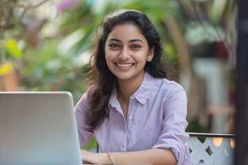 smiling indian woman student work wearing lilac collared shirt outside on laptop