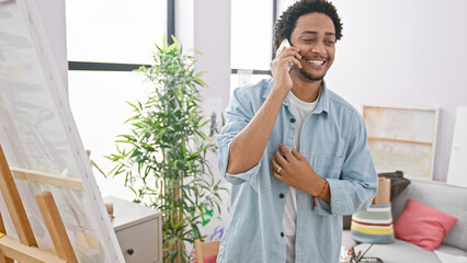 Smiling man talking on phone in a creative studio interior.