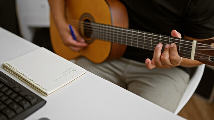 Passionate young latin man, a musician in the heart of his craft, composing a melody while holding a classical guitar in a cozy music studio