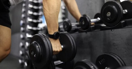 Male athlete with fitness watch on hand taking dumbbell for sports training in gym closeup 4k movie slow motion. Healthy lifestyle concept