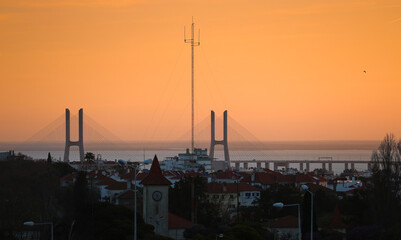 Vasco da Gama bridge in Lisbon during a beautiful summer sunrise. Orange sky sunrise with landmark...