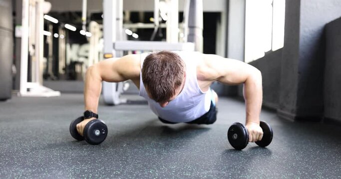 Man athlete doing push ups on dumbbells in gym 4k movie slow motion. Regular sorting load for body concept