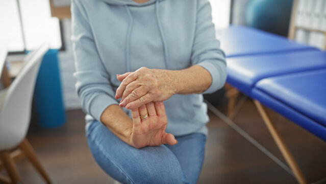 Mature woman exercising hand at a physiotherapy room, depicting healthcare and rehabilitation in an indoor setting.