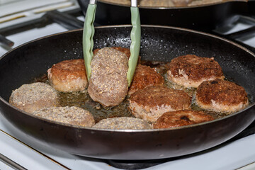 Kotlety mielone z wieprzowiny smażone na gorącym oleju rzepakowym na patelni 