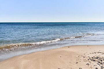 Tranquil beach scene with clear blue sky, golden sand, turquoise sea, and no people, depicting a serene holiday destination.