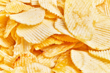 Close-up view of crispy, golden potato chips filling the frame, epitomizing snack and indulgence.