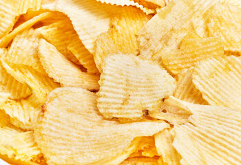 Close-up view of crispy yellow potato chips piled together showcasing snack and food concept.